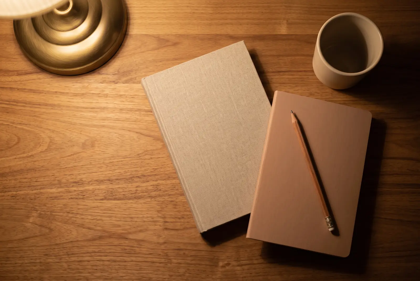 An open notebook of Arabic vocabulary beside an open mushaf on a desk.
